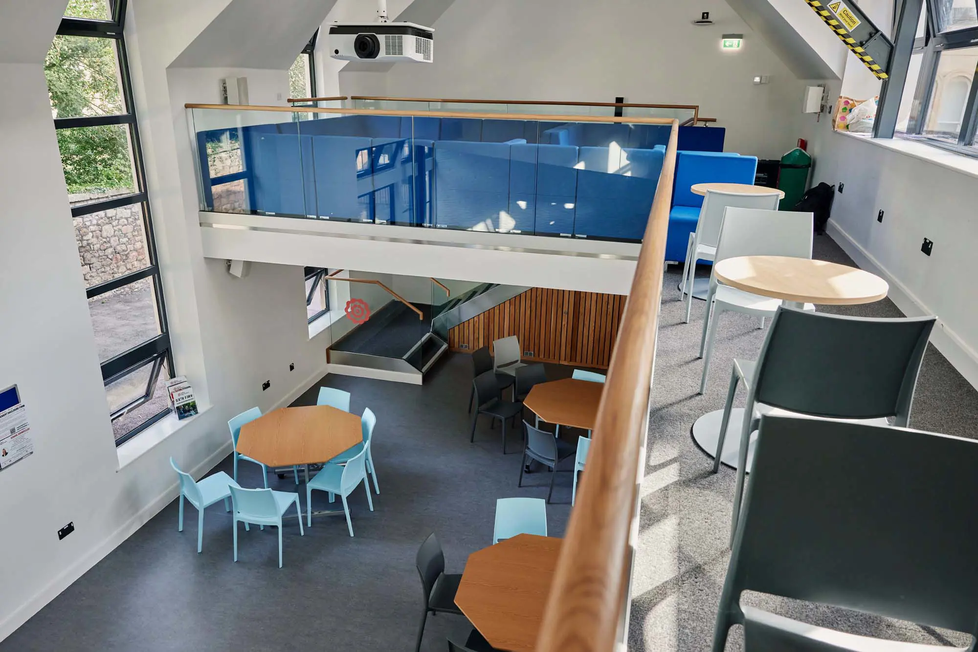 Modern social and study space inside Walter's Sixth Form Centre at Clifton High School, featuring collaborative seating, study tables and mezzanine-level work areas.