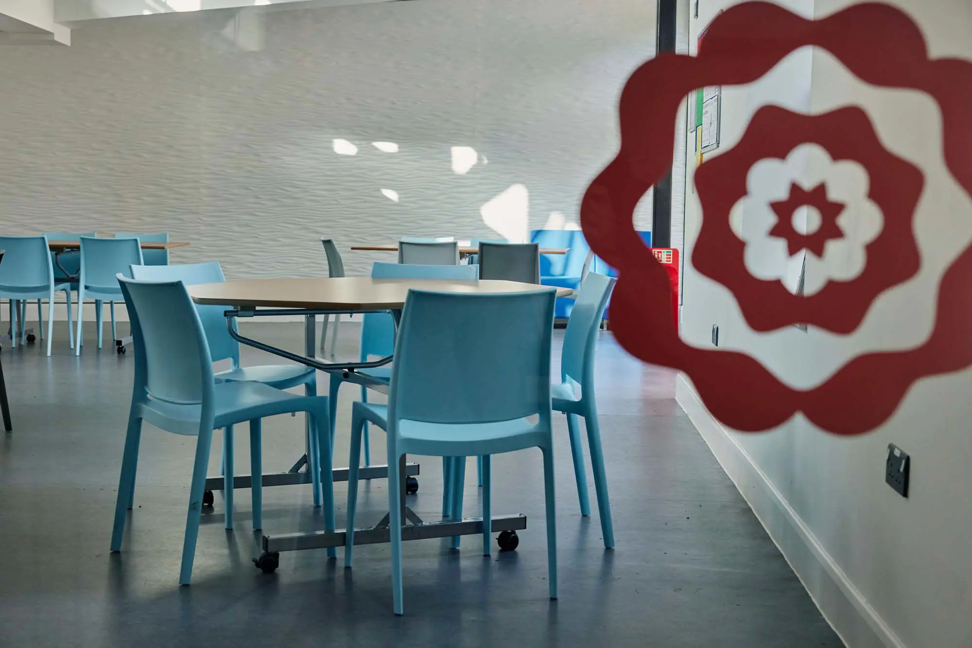 Modern social and study space inside Walter's Sixth Form Centre at Clifton High School, featuring collaborative seating, study tables, and mezzanine-level work areas.